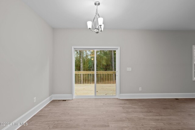 spare room with light wood-type flooring and an inviting chandelier