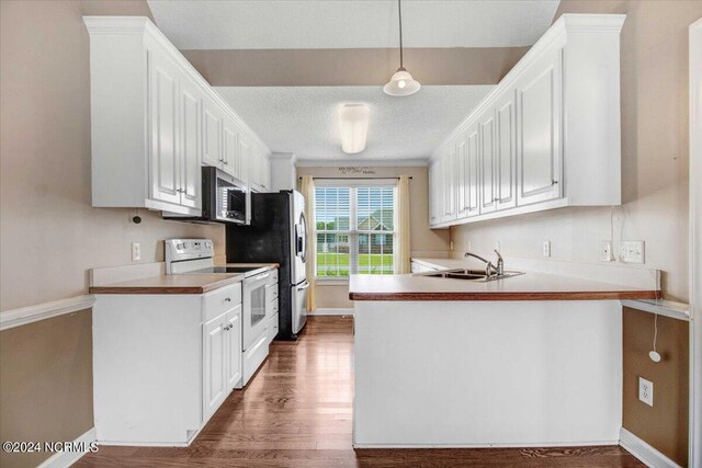 kitchen featuring pendant lighting, sink, white range with electric stovetop, dark hardwood / wood-style flooring, and kitchen peninsula