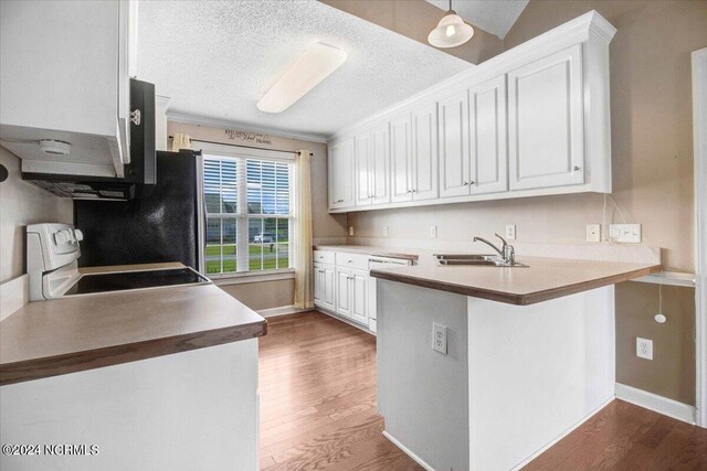 kitchen with kitchen peninsula, stove, a textured ceiling, white cabinets, and dark hardwood / wood-style floors