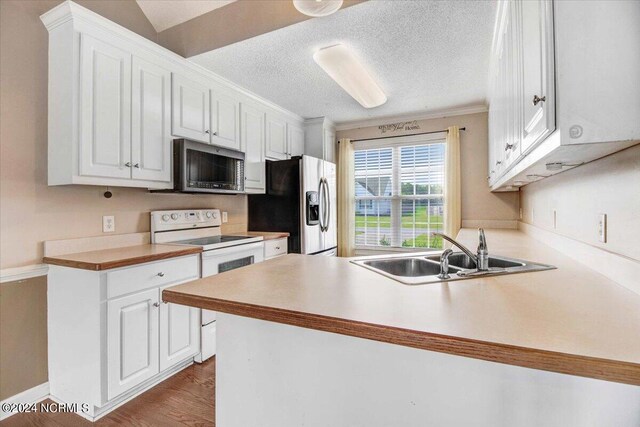 kitchen with white cabinets, sink, a textured ceiling, kitchen peninsula, and stainless steel appliances