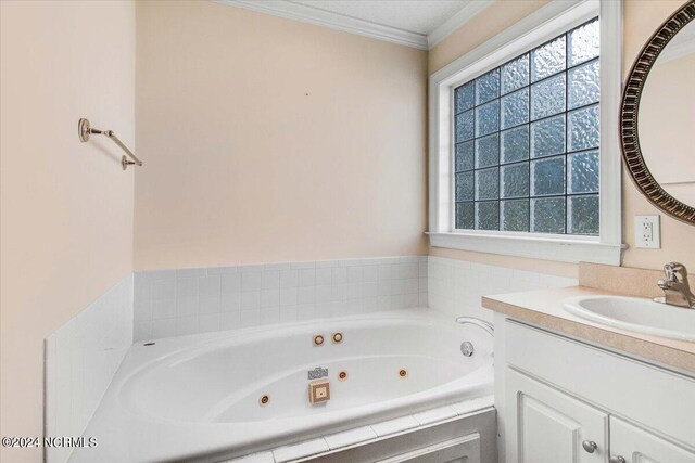 bathroom with tiled tub, vanity, and ornamental molding