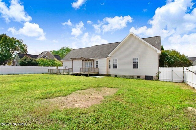 back of property featuring a lawn and a wooden deck