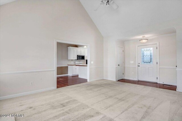 carpeted entrance foyer with high vaulted ceiling and ceiling fan