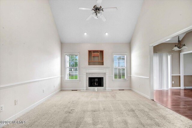 unfurnished living room featuring a premium fireplace, ceiling fan, wood-type flooring, and high vaulted ceiling