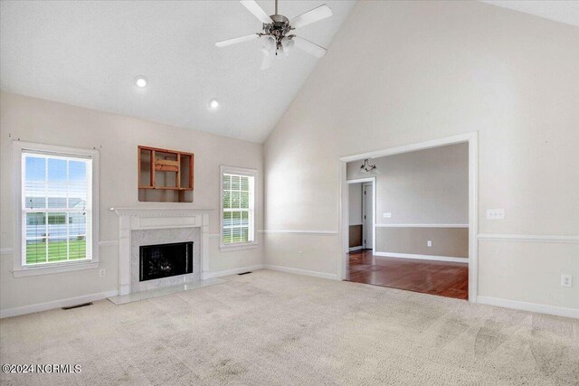 unfurnished living room with carpet, high vaulted ceiling, ceiling fan, and a premium fireplace