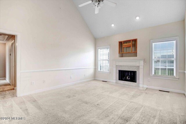 unfurnished living room featuring a high end fireplace, high vaulted ceiling, plenty of natural light, and ceiling fan