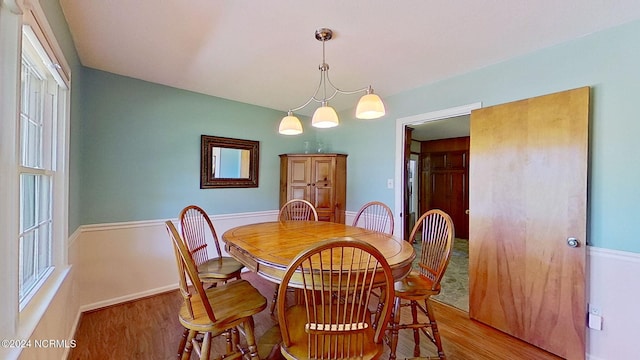 dining area with light hardwood / wood-style floors and a chandelier