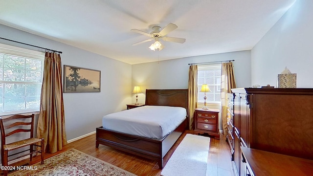 bedroom with ceiling fan, multiple windows, and hardwood / wood-style floors