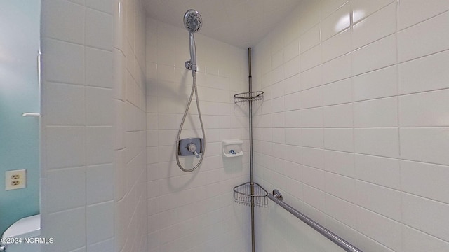 bathroom with a tile shower and toilet