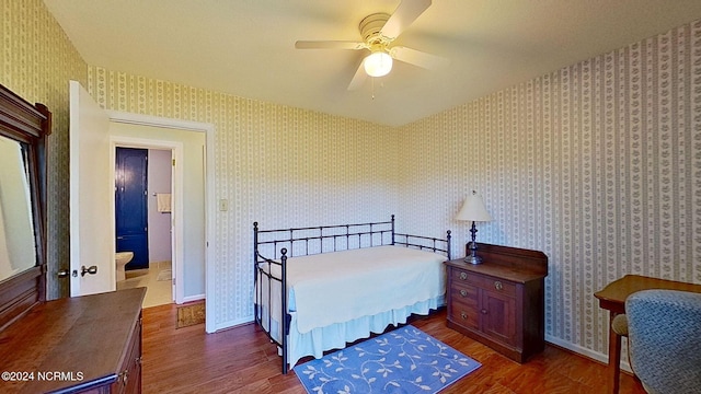 bedroom with ceiling fan, ensuite bath, and dark hardwood / wood-style flooring