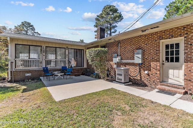 rear view of property with a patio and a lawn