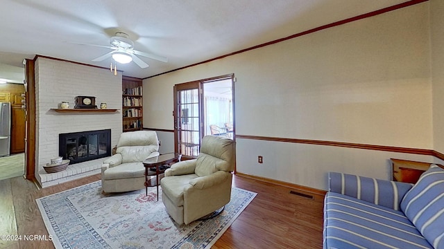 living room with ornamental molding, ceiling fan, a fireplace, and dark hardwood / wood-style flooring