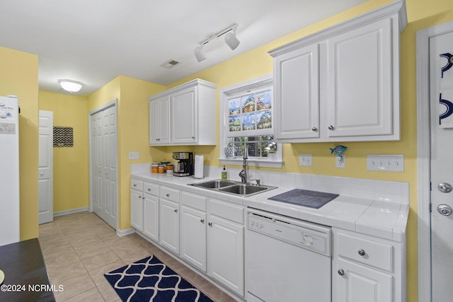 kitchen with white cabinets, light tile patterned flooring, sink, dishwasher, and tile counters