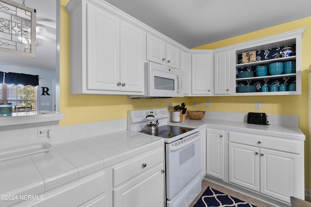 kitchen featuring white appliances, tile counters, and white cabinetry