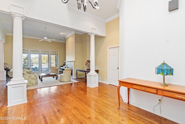 living room with a towering ceiling, crown molding, light hardwood / wood-style floors, and ceiling fan