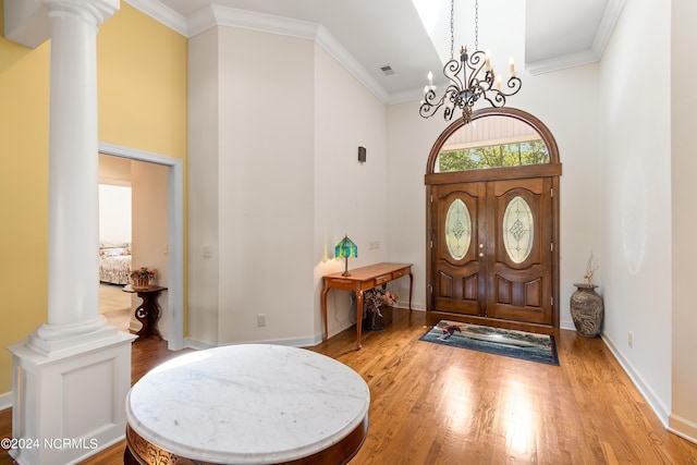 entryway featuring a high ceiling, hardwood / wood-style flooring, a chandelier, and ornate columns