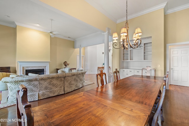 dining room with ornate columns, a premium fireplace, crown molding, ceiling fan with notable chandelier, and dark hardwood / wood-style flooring