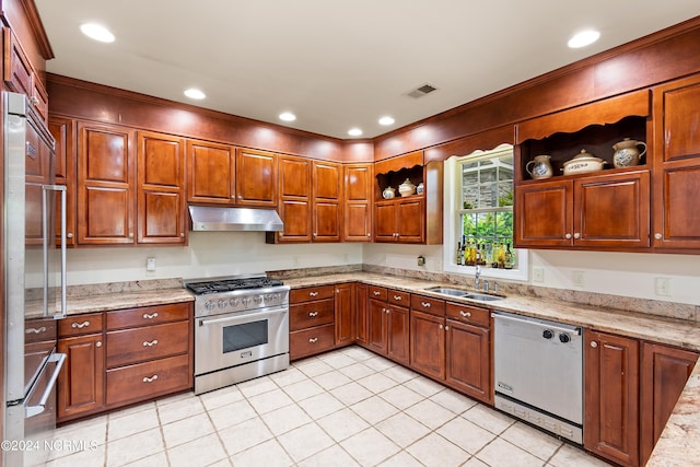 kitchen with sink, light tile patterned flooring, light stone counters, and premium appliances