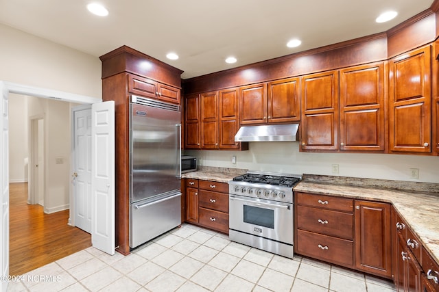 kitchen with light hardwood / wood-style floors, premium appliances, and light stone countertops