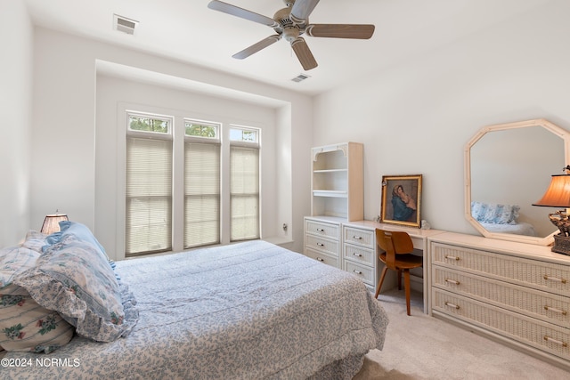 bedroom with light carpet, built in desk, and ceiling fan