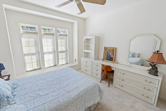 bedroom with light carpet, built in desk, and ceiling fan