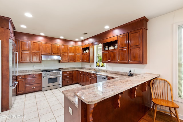 kitchen with light tile patterned floors, sink, kitchen peninsula, a breakfast bar, and high end appliances