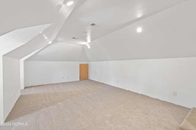 additional living space featuring light carpet and vaulted ceiling