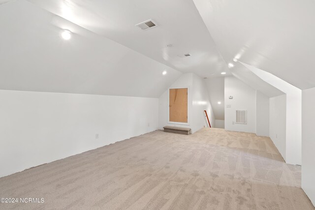 additional living space featuring vaulted ceiling and light colored carpet