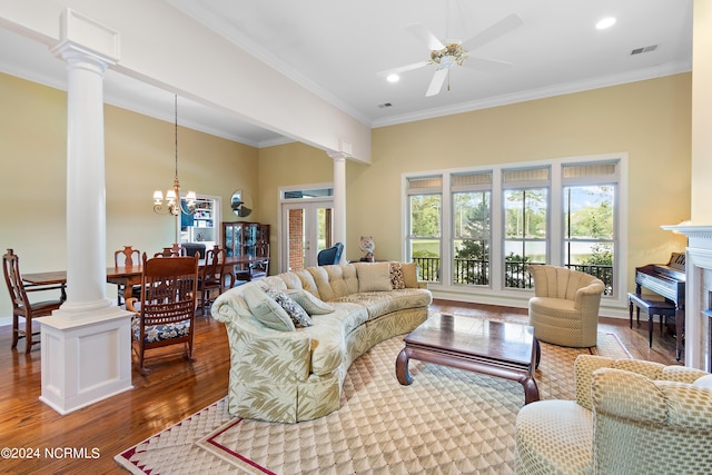 living room with crown molding, wood-type flooring, ceiling fan with notable chandelier, and decorative columns