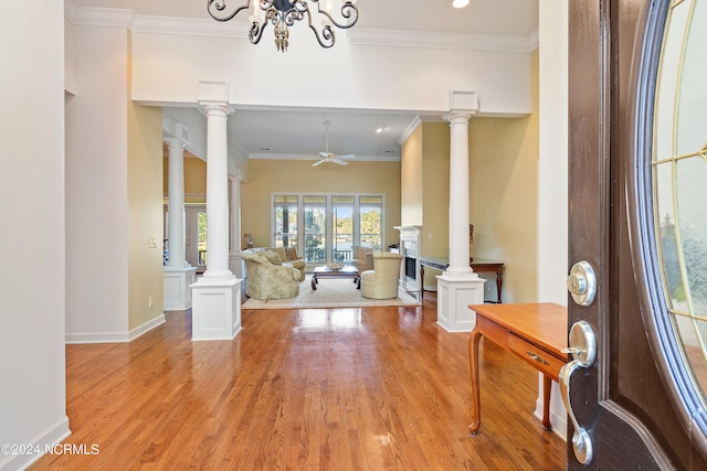 interior space featuring crown molding, ceiling fan with notable chandelier, light hardwood / wood-style floors, and decorative columns