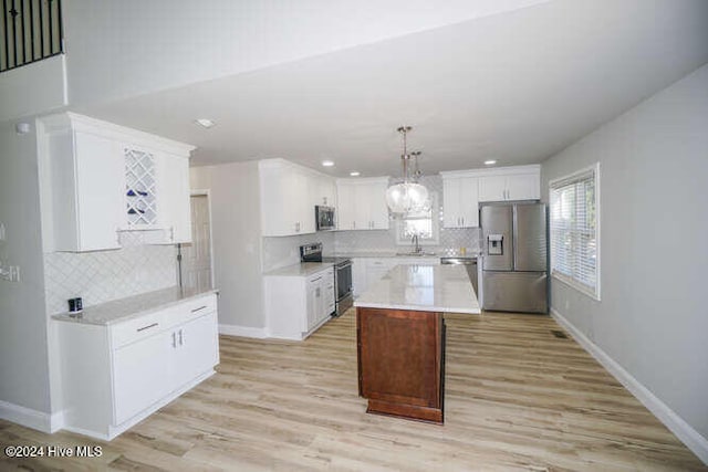 kitchen with hanging light fixtures, a kitchen island, appliances with stainless steel finishes, and light countertops