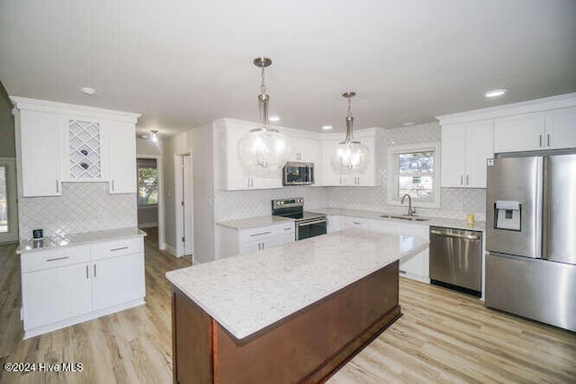 kitchen with hanging light fixtures, white cabinetry, stainless steel appliances, and a center island