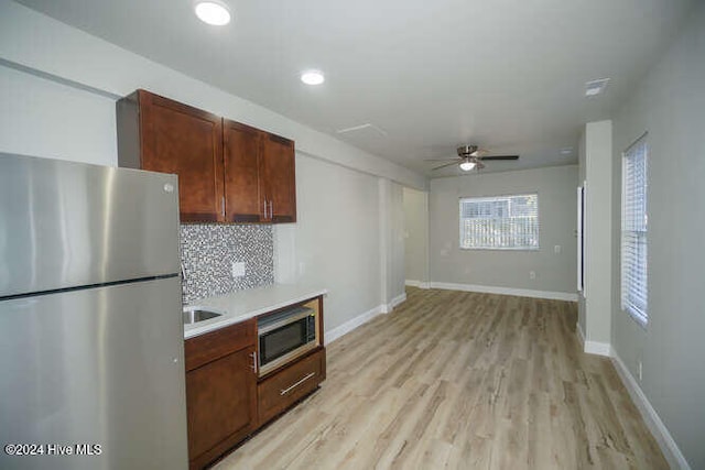 kitchen featuring stainless steel appliances, baseboards, light wood-style floors, light countertops, and decorative backsplash