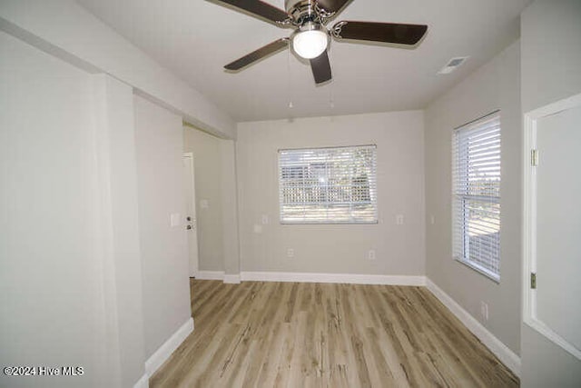 empty room with visible vents, light wood-style flooring, and baseboards