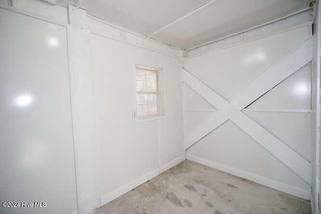 empty room with baseboards and unfinished concrete flooring