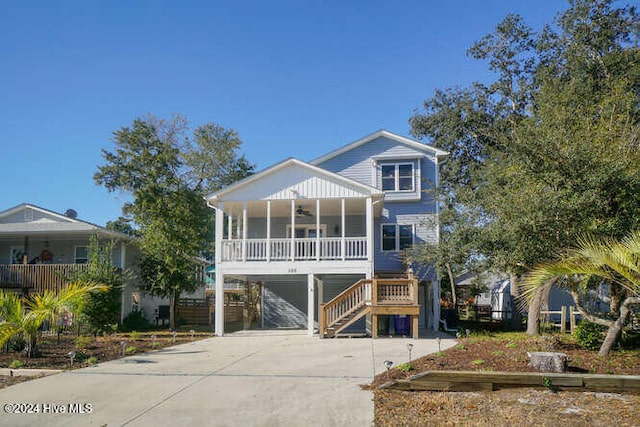 coastal inspired home with covered porch, a ceiling fan, driveway, stairway, and a carport