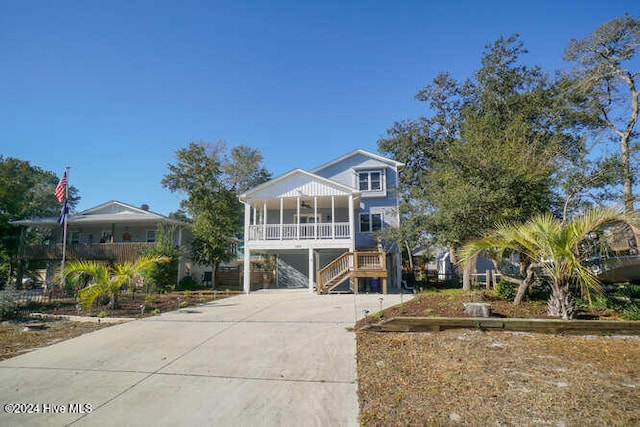 coastal inspired home with a sunroom, covered porch, driveway, and stairs