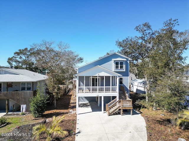 coastal home featuring driveway, stairs, and a porch