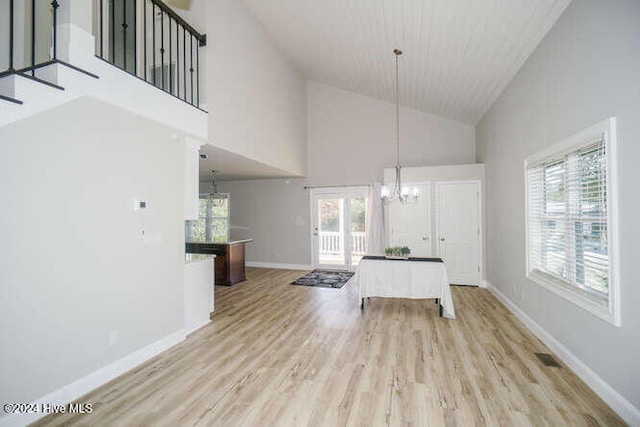 unfurnished dining area featuring baseboards, light wood finished floors, a wealth of natural light, and a notable chandelier