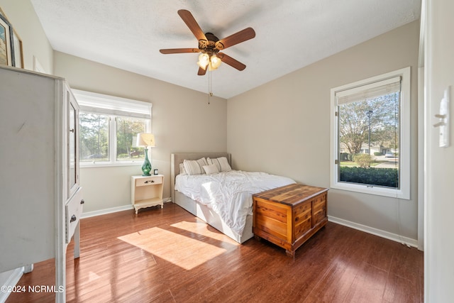 bedroom with a textured ceiling, wood finished floors, a ceiling fan, and baseboards