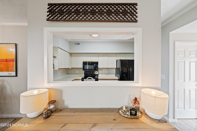 kitchen with light countertops, visible vents, ornamental molding, a textured ceiling, and black appliances