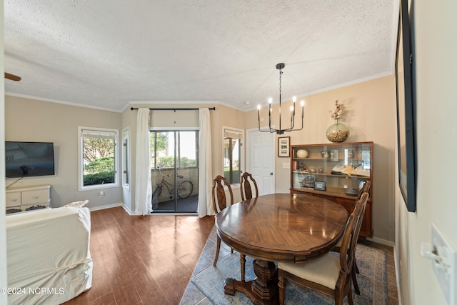 dining area with a textured ceiling, a notable chandelier, wood finished floors, baseboards, and ornamental molding