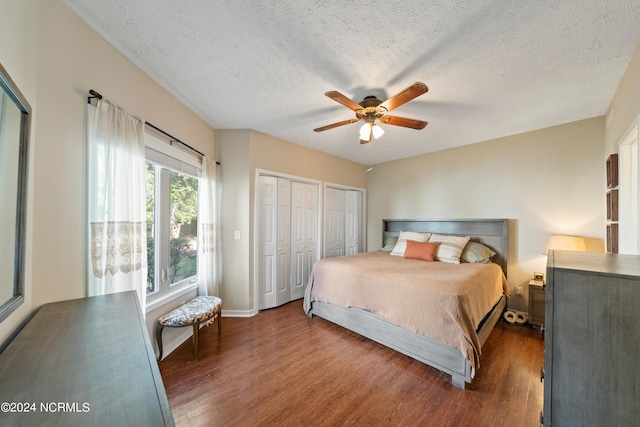 bedroom with multiple closets, ceiling fan, dark hardwood / wood-style floors, and a textured ceiling