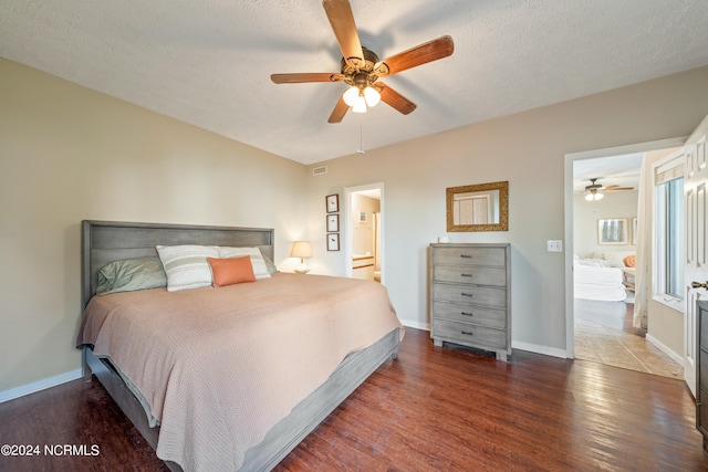 bedroom with a textured ceiling, ceiling fan, dark wood-type flooring, and ensuite bathroom