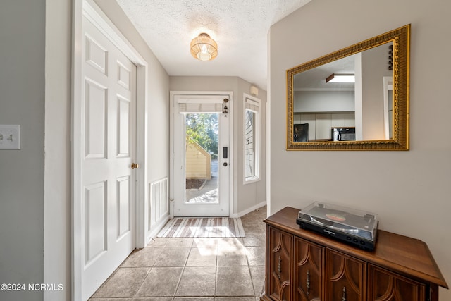 entryway with visible vents, a textured ceiling, baseboards, and light tile patterned flooring