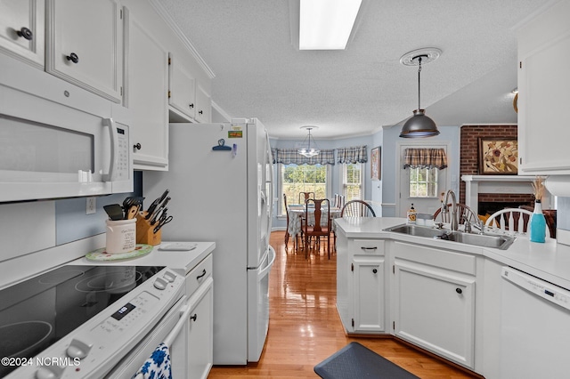 kitchen with hanging light fixtures, white cabinetry, white appliances, light wood-type flooring, and a textured ceiling