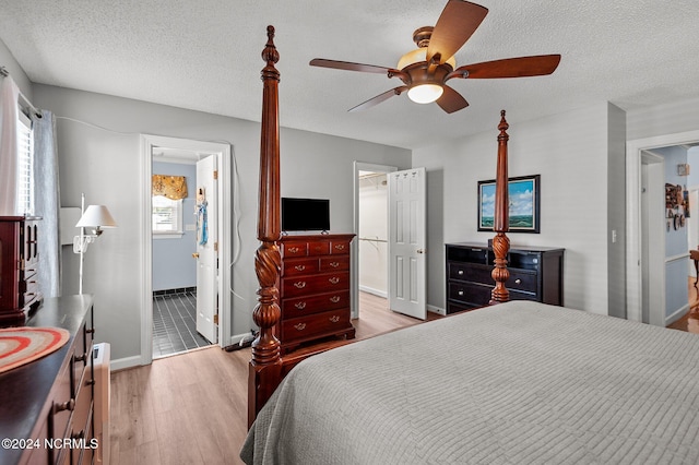 bedroom with connected bathroom, ceiling fan, light wood-type flooring, and a textured ceiling