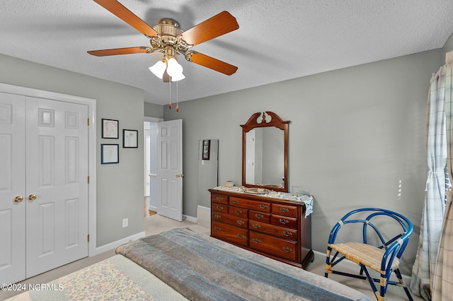 bedroom featuring a closet, ceiling fan, light colored carpet, and a textured ceiling