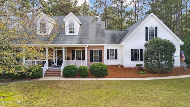 cape cod home featuring a front yard and a porch