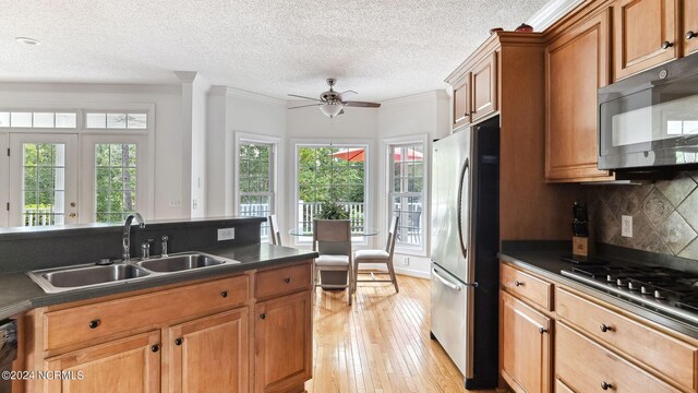 dining space with ceiling fan, sink, crown molding, light hardwood / wood-style flooring, and a textured ceiling